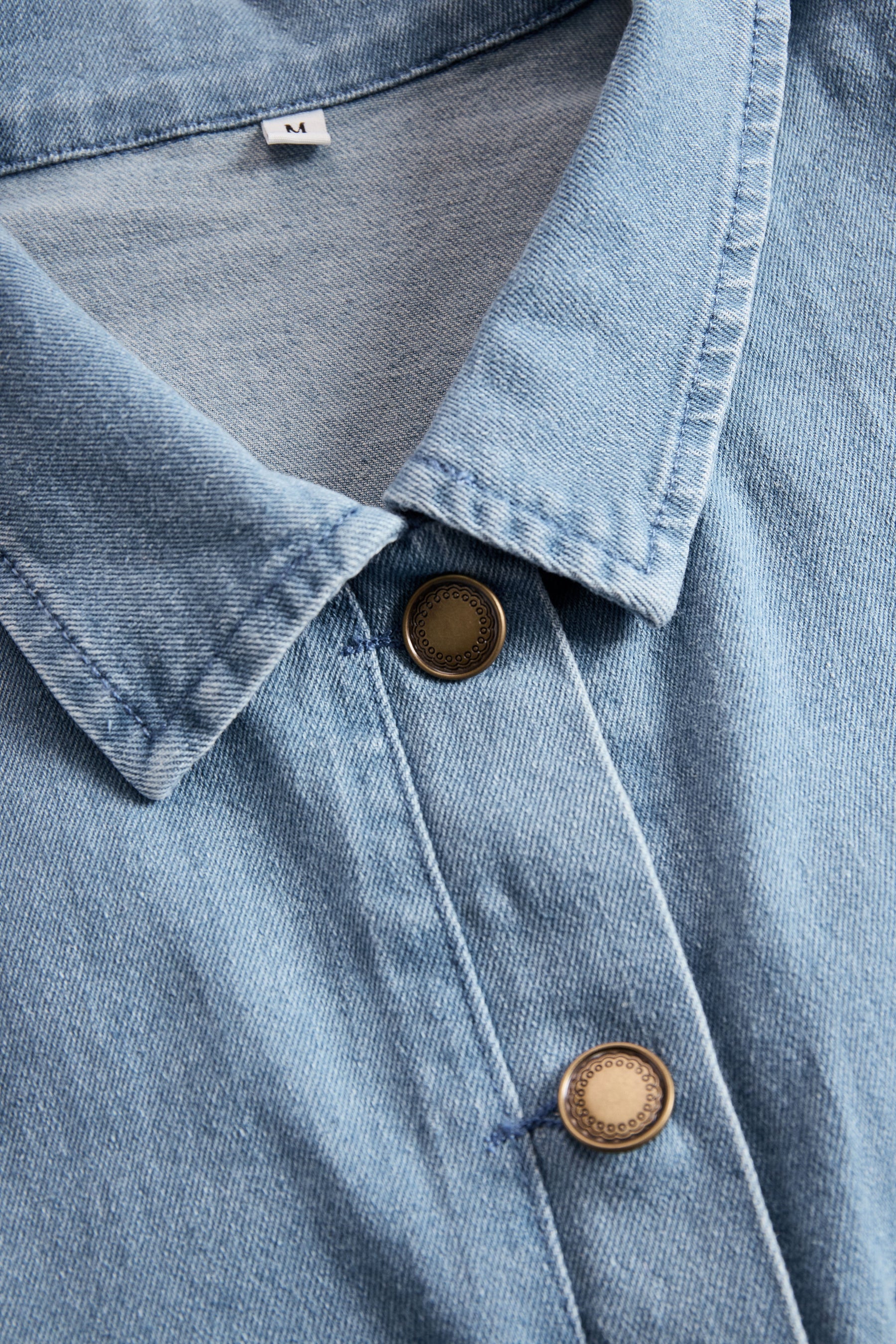 Light blue denim sleeveless jumpsuit with raw edge wide-leg pants, designed for women, featuring a stylish and casual look.