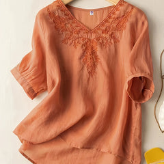 Light blue V-neck linen summer blouse for women, flowing and casual, displayed on a hanger with a relaxed fit.