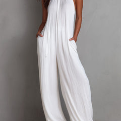 White pleated halter neck wide-leg resort jumpsuit for women, featuring stylish pants with a relaxed fit and elegant design.