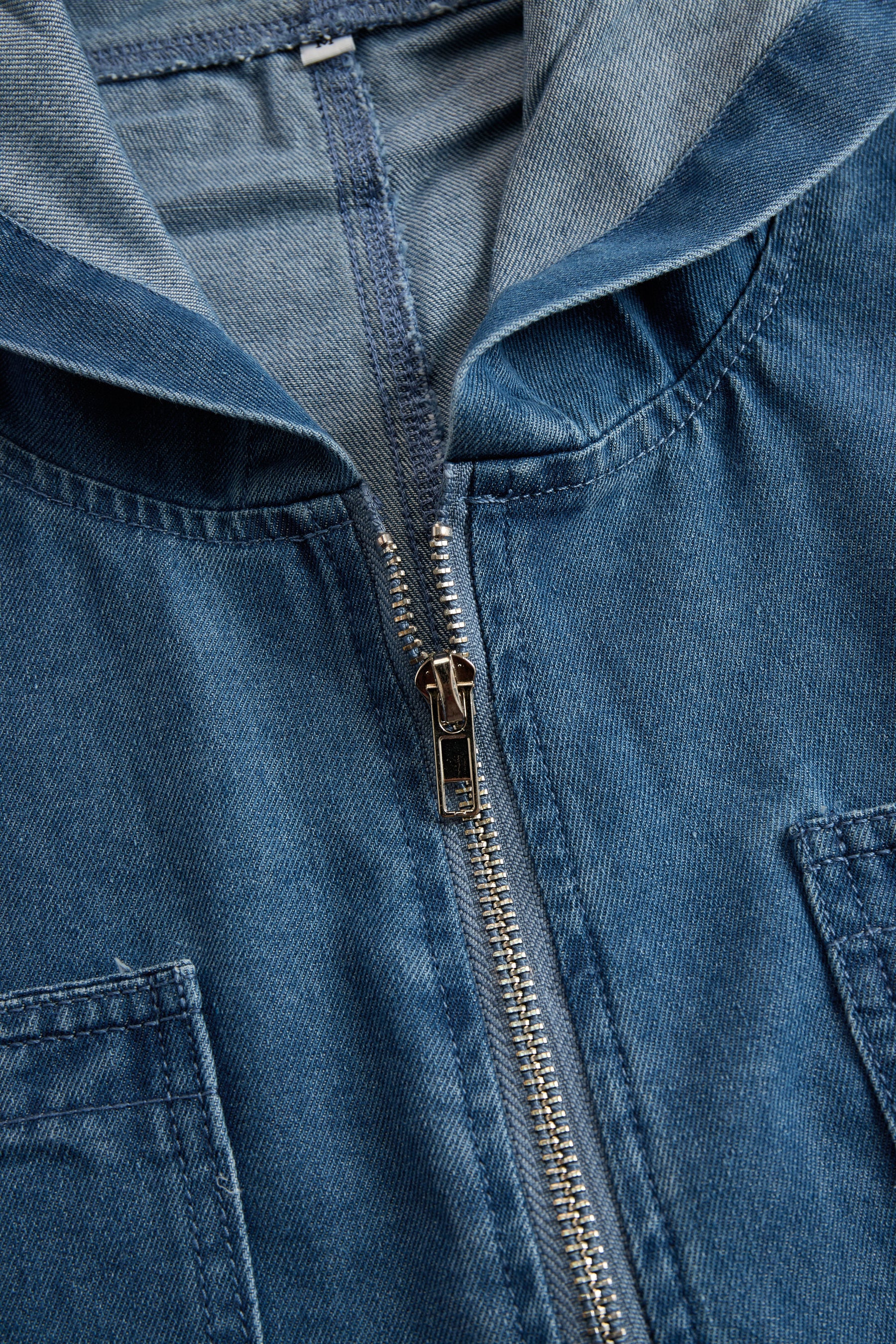 Women’s casual loose retro denim jumpsuit with long sleeves, hood, zipper, and pockets, featuring a relaxed fit and stylish design.