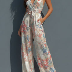 White floral satin women’s halter neck jumpsuit with wrap front and wide-leg pants, featuring a stylish and elegant design.