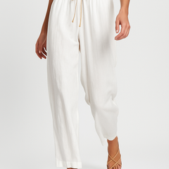 Light beige tapered linen trousers for women, loose pull-on style, shown in motion with casual fit and relaxed silhouette.