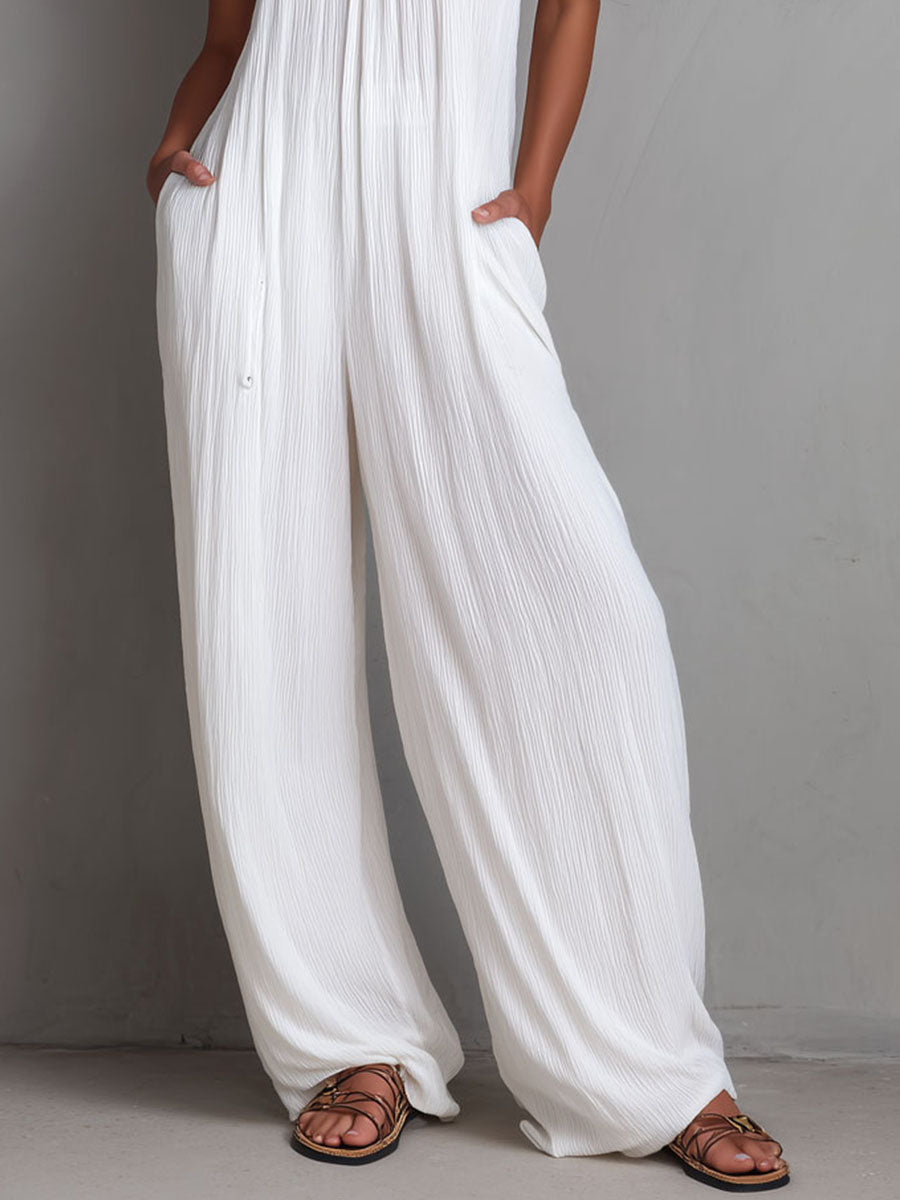 White pleated halter neck wide-leg resort jumpsuit for women, featuring stylish pants with a relaxed fit and elegant design.