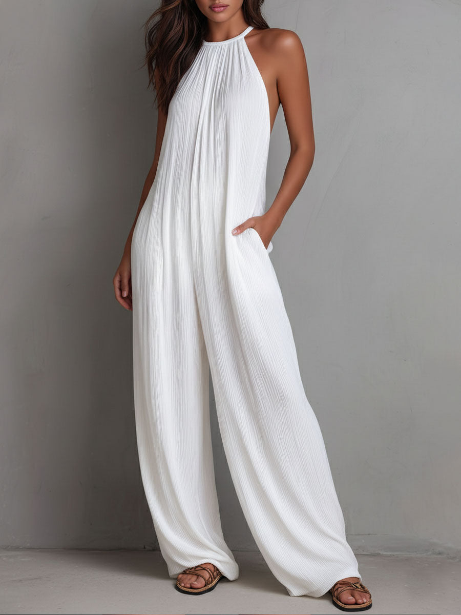 White pleated halter neck wide-leg resort jumpsuit for women, featuring stylish pants with a flowy, comfortable fit.