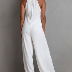 White pleated halter neck wide-leg resort jumpsuit for women, stylish pants with flowing fabric and halter neckline.