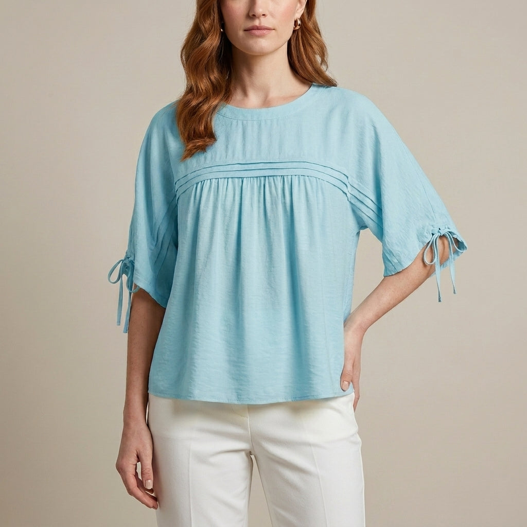 Blue linen summer blouse for women, flowy and lightweight, styled with short sleeves and a relaxed fit.