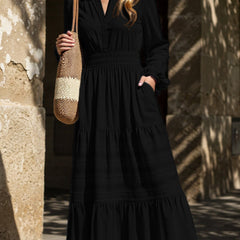 Black V-neck pleated waist tiered long-sleeved dress with a flowing silhouette, featuring a stylish design suitable for various occasions.