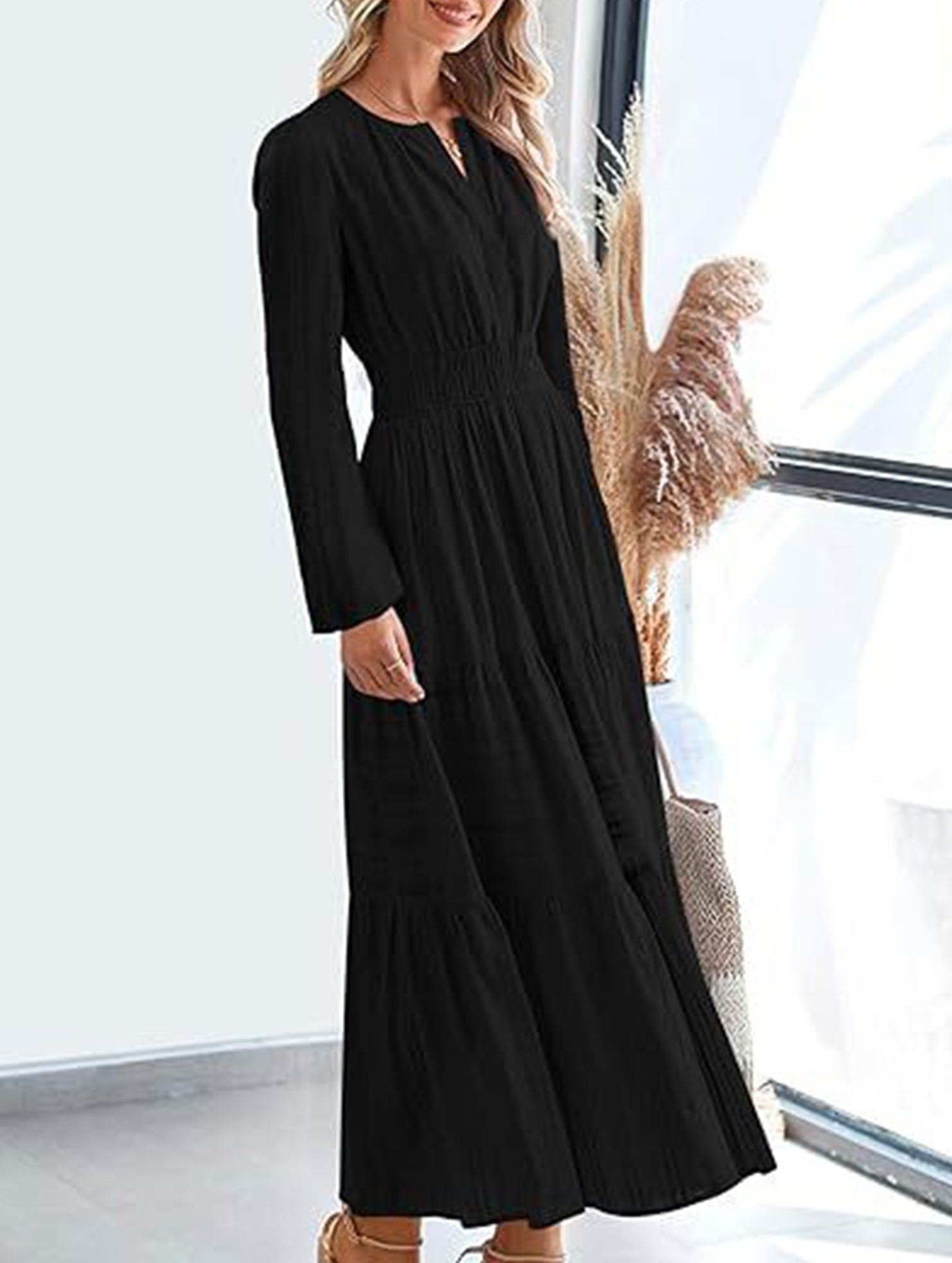 Black V-neck pleated waist tiered long-sleeved dress with a flowing silhouette, perfect for elegant occasions.