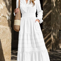 White V-neck pleated waist tiered long-sleeved dress with flowing fabric and elegant design, perfect for stylish occasions.
