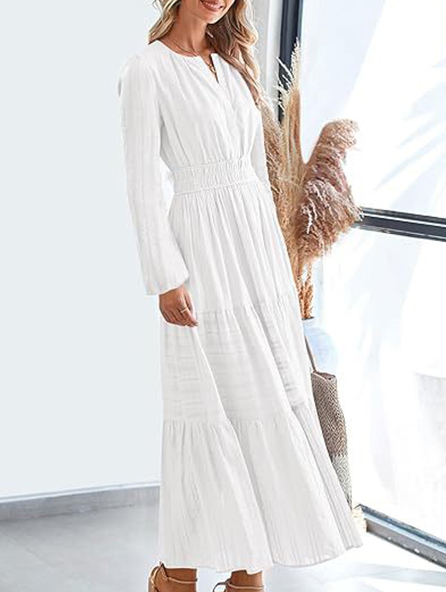 White V-neck pleated waist tiered long-sleeved dress with flowing fabric and a fitted waist, perfect for elegant occasions.