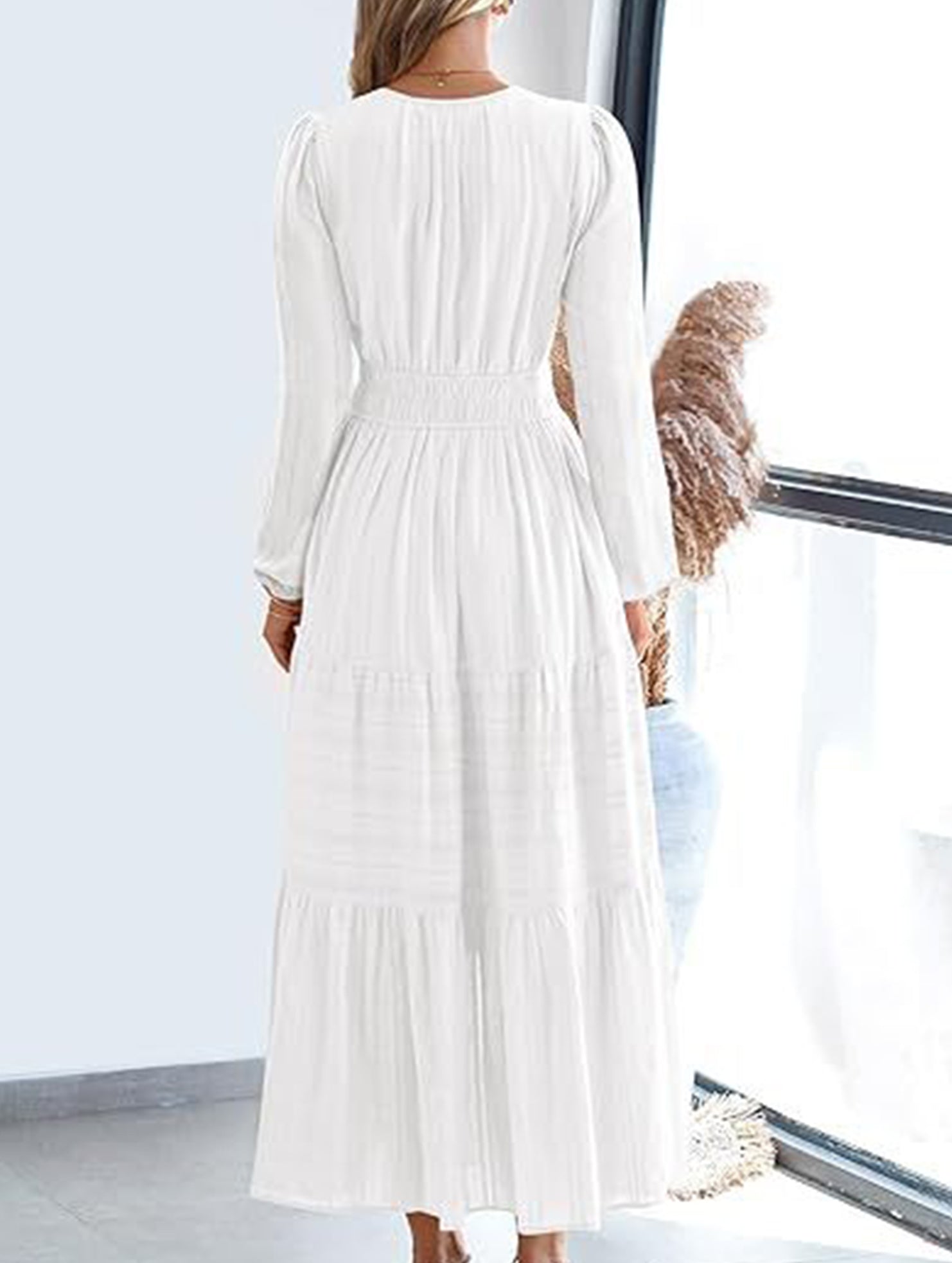 White V-neck pleated waist tiered long-sleeved dress with a flowing silhouette and elegant design.