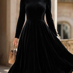 Black velvet long-sleeved round neck dress by Tammy Bradley, showcasing a sleek, fitted design with a smooth fabric finish.