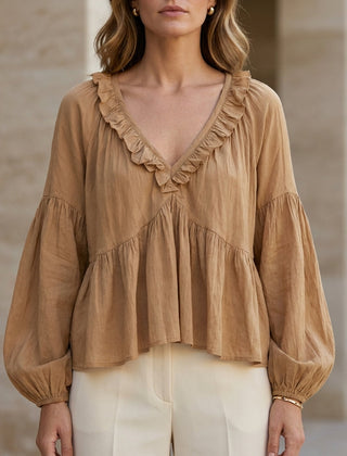 Light brown women's summer blouse with v-neck, long sleeves, and ruffle details, made of denim fabric.