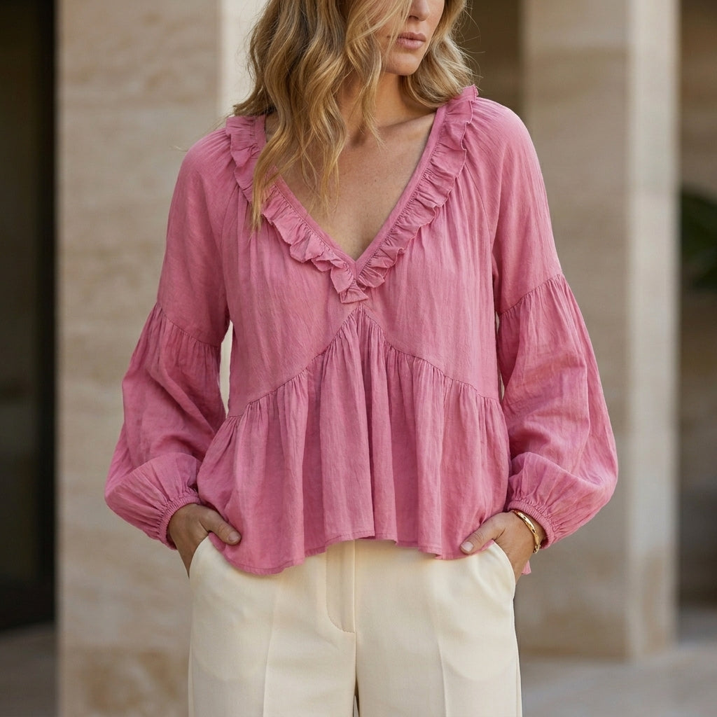 Pink women's summer blouse with V-neck, long sleeves, and ruffle details, made from denim fabric.