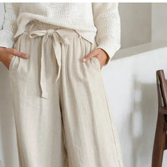 Light beige linen wide-leg women's trousers with a loose fit and pull-on design, styled with a relaxed, casual look.