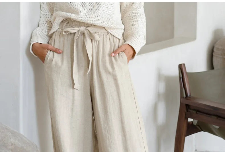 Light beige linen wide-leg women's trousers with a loose fit and pull-on design, styled with a relaxed, casual look.