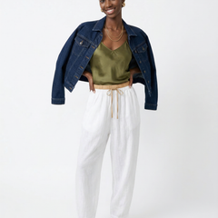 Light beige tapered linen trousers for women with a loose fit and pull-on style, displayed on a model.